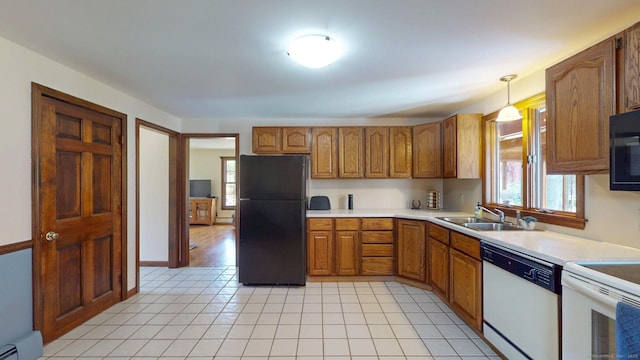 kitchen with brown cabinetry, a sink, a wealth of natural light, and white appliances