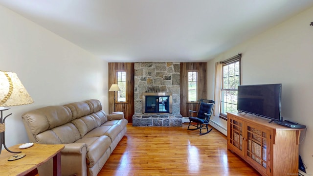 living room with light wood-style floors, baseboard heating, and a fireplace