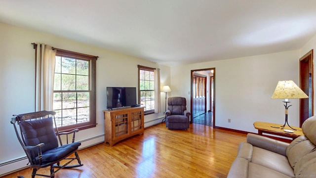 living area featuring baseboards, a baseboard heating unit, and light wood finished floors