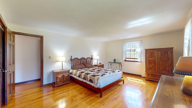 bedroom featuring light wood-style floors, baseboards, and baseboard heating