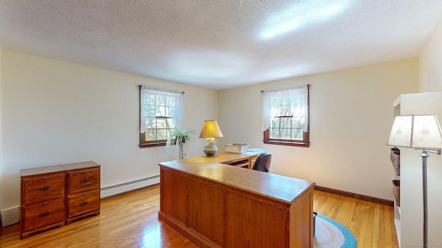 office space with light wood-style floors, baseboards, a textured ceiling, and a baseboard heating unit