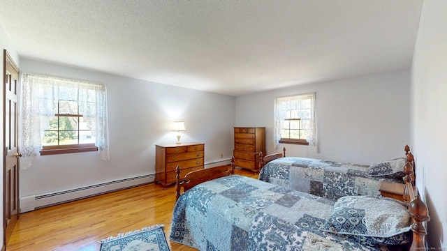 bedroom featuring a baseboard heating unit and wood finished floors