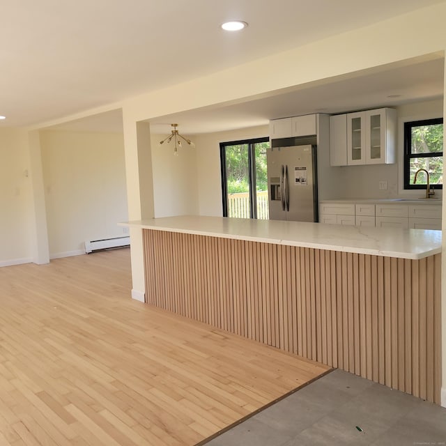 91 Jennifer Rd, Hamden, CT 06514 - kitchen featuring stainless steel refrigerator with ice dispenser, a sink, a baseboard heating unit, glass insert cabinets, and healthy amount of natural light