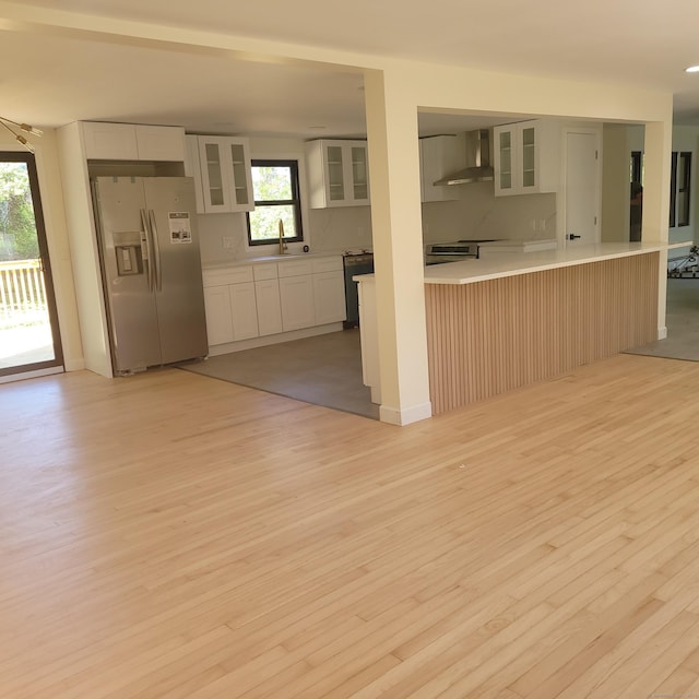 91 Jennifer Rd, Hamden, CT 06514 - kitchen with stainless steel fridge with ice dispenser, wall chimney range hood, light wood-style flooring, white cabinetry, and glass insert cabinets