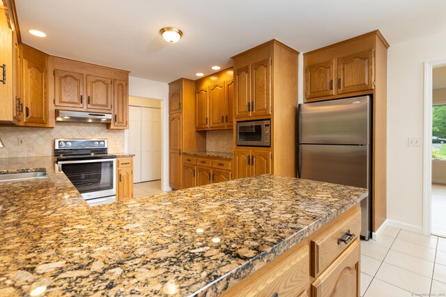 39 Amato Cir, Southington, CT 06489 - kitchen with stainless steel appliances, under cabinet range hood, light tile patterned floors, tasteful backsplash, and light stone countertops