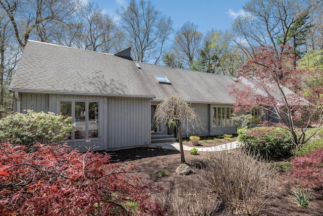 back of house featuring board and batten siding and roof with shingles