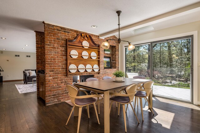 dining room featuring a brick fireplace, hardwood / wood-style floors, recessed lighting, baseboards, and visible vents