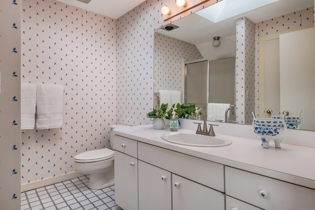 bathroom featuring a skylight, a stall shower, vanity, toilet, and wallpapered walls