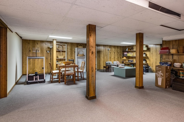 finished below grade area with carpet floors, a drop ceiling, and wood walls