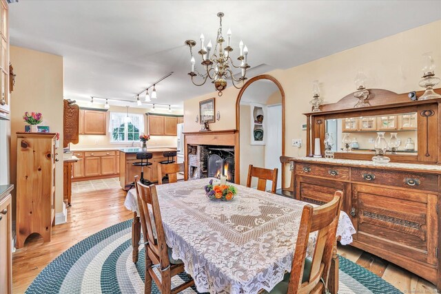 331 Elm St, Monroe, CT 06468 - dining space with light wood finished floors, arched walkways, a chandelier, track lighting, and a glass covered fireplace