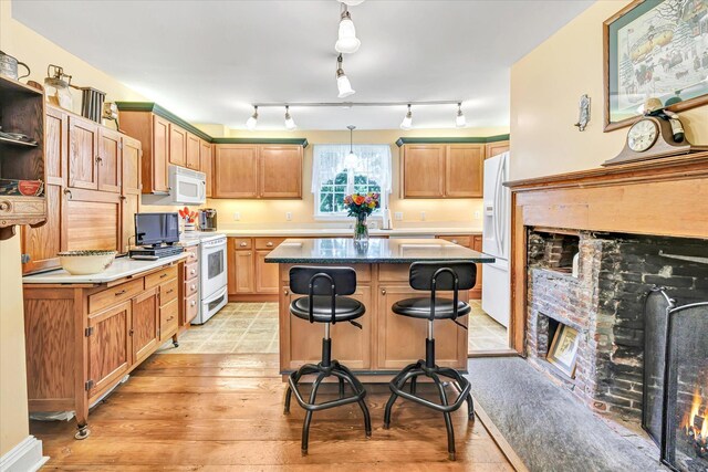 331 Elm St, Monroe, CT 06468 - kitchen with white appliances, a center island, light wood-style flooring, a kitchen breakfast bar, and a warm lit fireplace