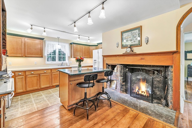331 Elm St, Monroe, CT 06468 - kitchen with white fridge with ice dispenser, a kitchen island, a lit fireplace, light wood finished floors, and track lighting