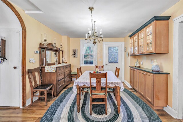331 Elm St, Monroe, CT 06468 - dining room featuring a chandelier, light wood-style flooring, baseboards, and arched walkways