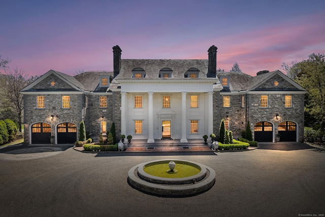 view of front of house featuring curved driveway, a high end roof, and stone siding