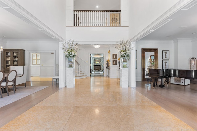 entrance foyer featuring crown molding, a towering ceiling, a decorative wall, and stairway