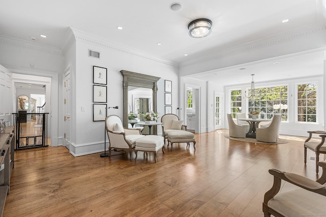 living area featuring visible vents, crown molding, wood finished floors, baseboards, and recessed lighting