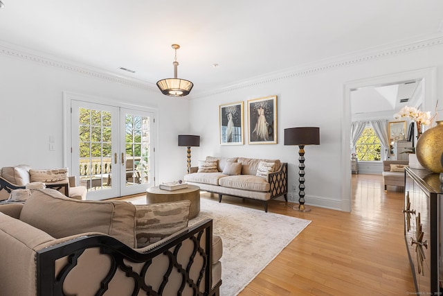 living area featuring french doors, ornamental molding, and light wood-style floors