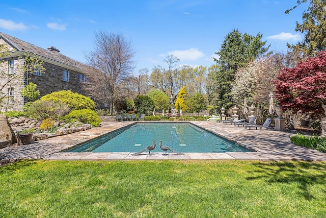 outdoor pool with a yard and a patio area
