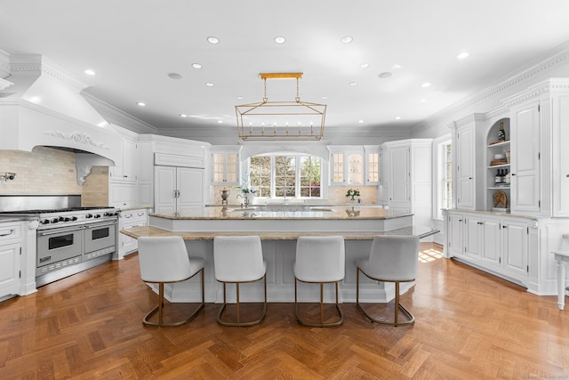 2959 Congress St, Fairfield, CT 06824 - kitchen featuring white cabinetry, a breakfast bar, and range with two ovens