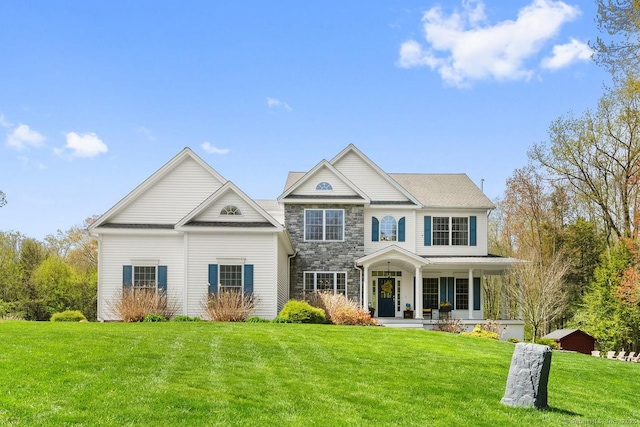 view of front of property with covered porch, a front lawn, and stone siding