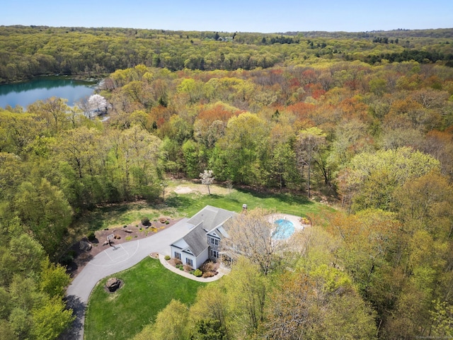aerial view of property and surrounding area with a heavily wooded area and a large body of water
