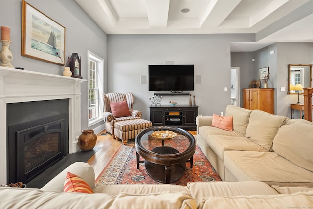 living area featuring wood finished floors, coffered ceiling, beam ceiling, and a fireplace with flush hearth