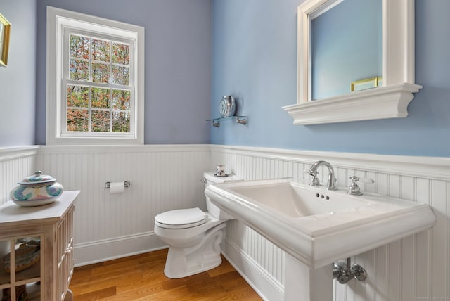 bathroom featuring wainscoting, toilet, a sink, and wood finished floors