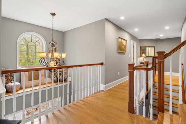 hall with wood finished floors, baseboards, a chandelier, and recessed lighting