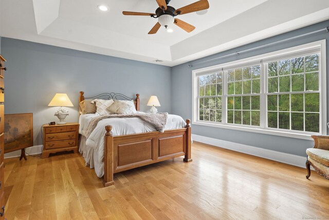 bedroom featuring a raised ceiling, baseboards, light wood-type flooring, ceiling fan, and recessed lighting