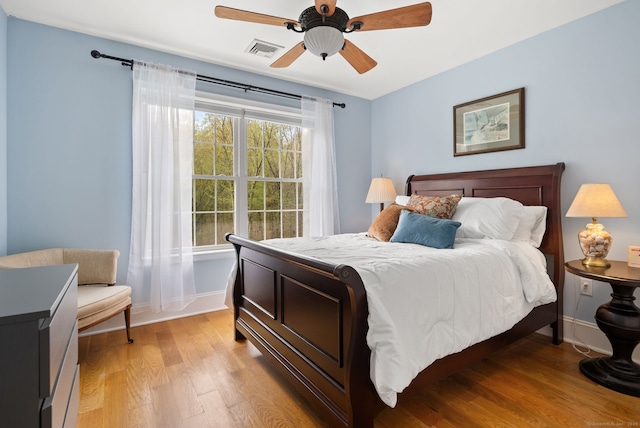 bedroom featuring light wood-type flooring, baseboards, and a ceiling fan