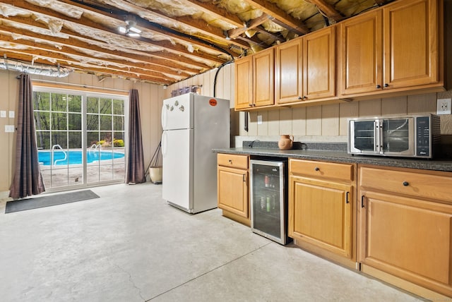 kitchen with freestanding refrigerator, wine cooler, finished concrete floors, and dark countertops