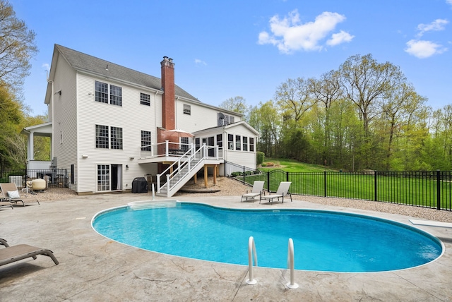 view of pool with a sunroom, stairway, a patio, and a wooden deck