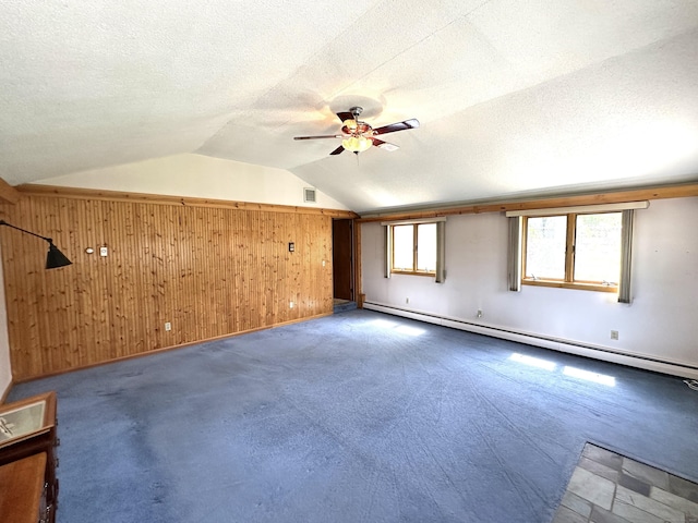 bonus room featuring ceiling fan, wooden walls, a textured ceiling, a baseboard radiator, and vaulted ceiling