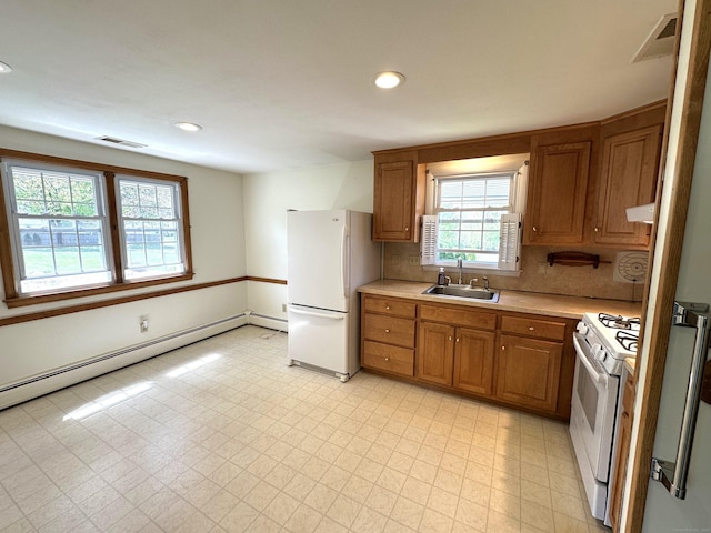 kitchen with baseboard heating, a sink, white appliances, light countertops, and visible vents