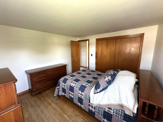 bedroom featuring a closet, wood finished floors, and visible vents