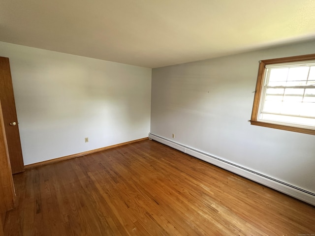 unfurnished room featuring baseboards, a baseboard radiator, and wood finished floors