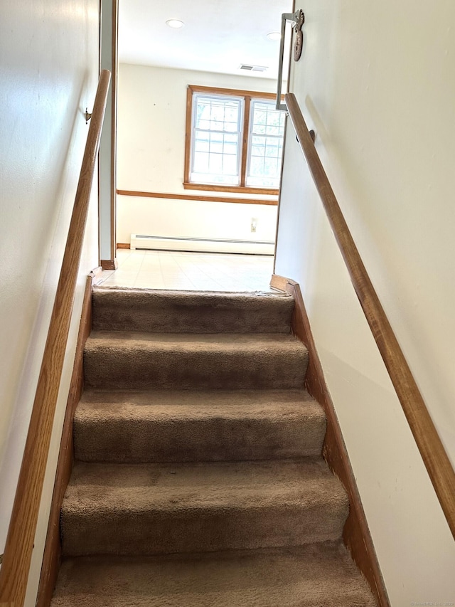 staircase featuring carpet floors, visible vents, and baseboard heating