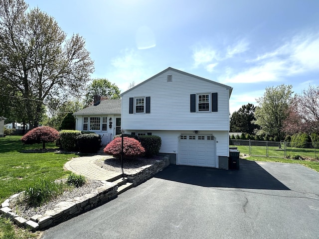 view of property exterior with fence, an attached garage, a lawn, and driveway