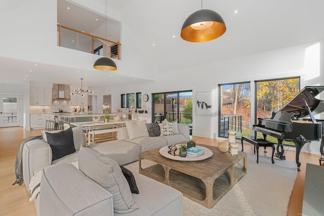 living area with recessed lighting, light wood-style floors, a notable chandelier, and high vaulted ceiling