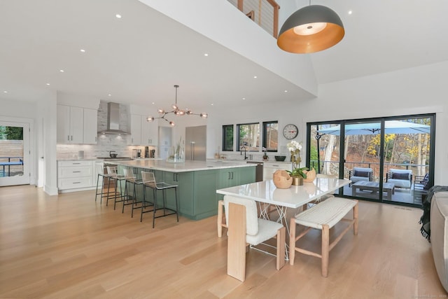 dining room with plenty of natural light, light wood-style flooring, and a towering ceiling