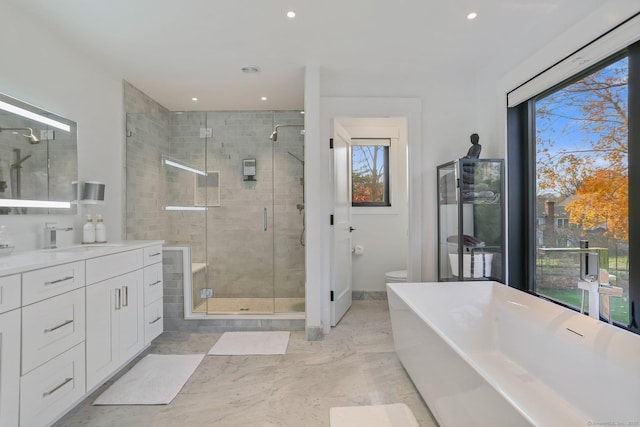 bathroom featuring a freestanding bath, vanity, toilet, marble finish floor, and a shower stall