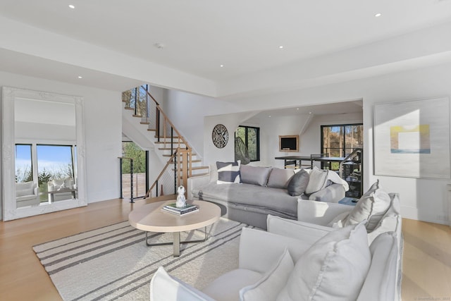 living room featuring recessed lighting, baseboards, wood finished floors, and stairway