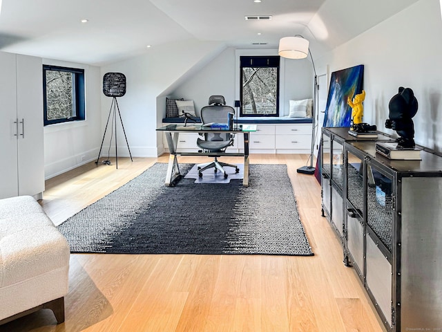 home office with visible vents, baseboards, lofted ceiling, and light wood finished floors