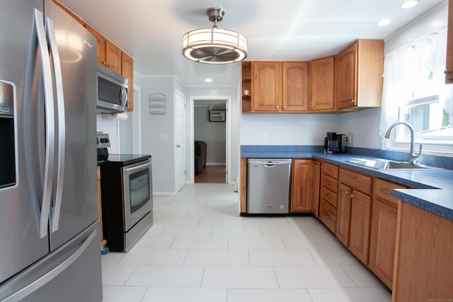 kitchen featuring brown cabinetry, pendant lighting, dark countertops, a sink, and stainless steel appliances