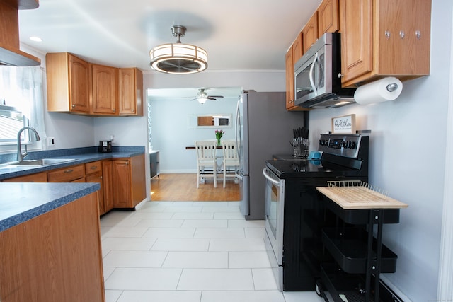 kitchen with a sink, dark countertops, brown cabinets, a ceiling fan, and appliances with stainless steel finishes