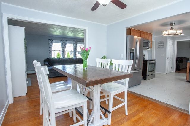 dining space featuring a baseboard radiator, ceiling fan, and light wood-type flooring