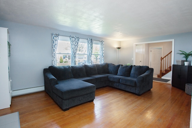 living area featuring light wood-style floors, a baseboard radiator, and stairway
