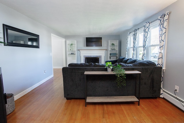 living room with a fireplace, baseboard heating, built in shelves, wood finished floors, and baseboards