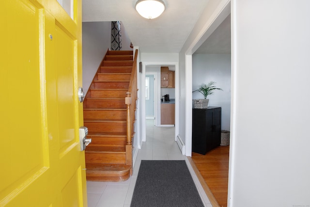 entrance foyer featuring stairs, baseboard heating, and light tile patterned floors