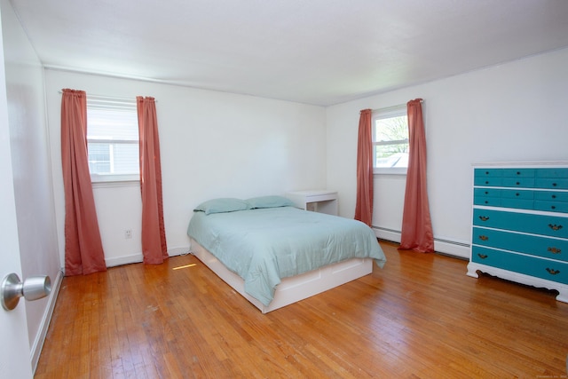 bedroom featuring baseboards, a baseboard heating unit, and light wood-type flooring
